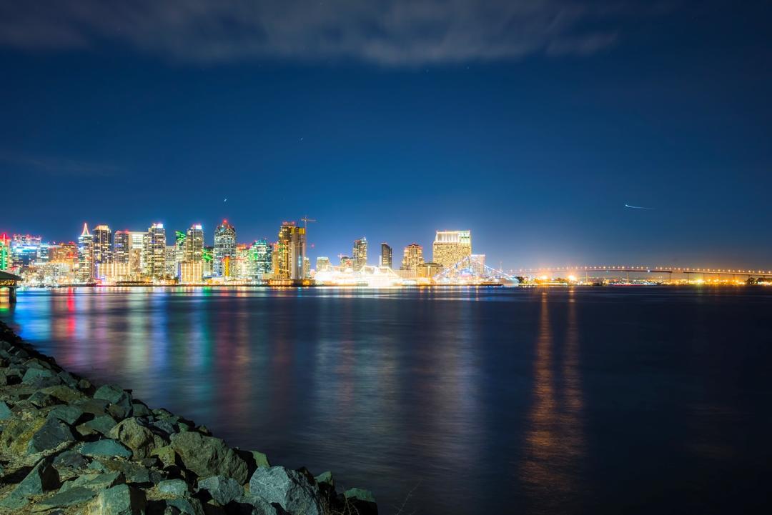 the San Diego skyline lights up at night and reflects off of the bay