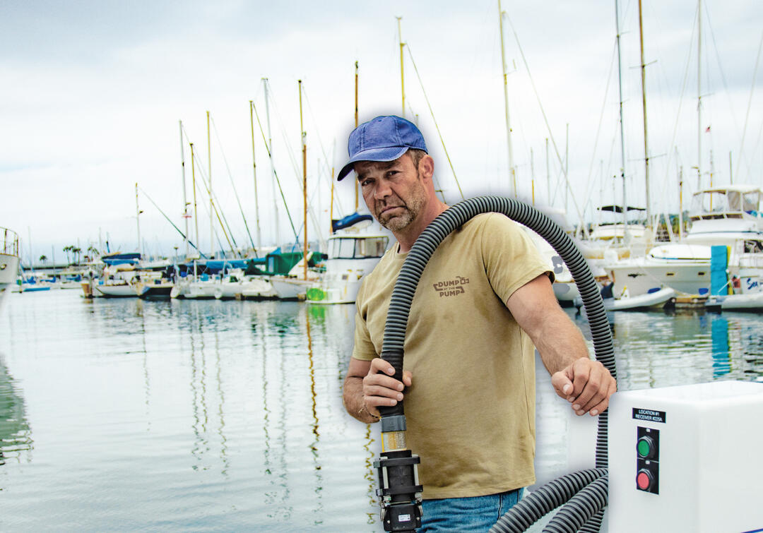 a burly man hauls a pump out hose on a waterside dock