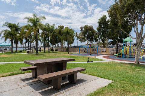 A park with a picnic table, grass, and playground.