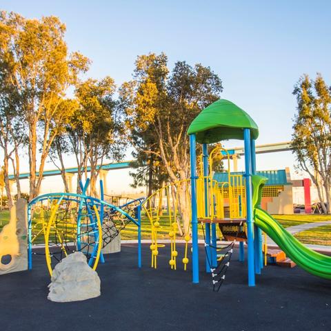 Playground with trees and Coronado Bridge in the background at Cesar Chavez Park at the Port of San Diego