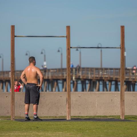 Man working out at exercise station hanging bars at Portwood Pier Plaza at the Port of San Diego