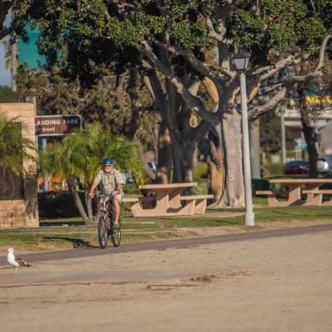 Cyclist biking past picnic tables at Spanish Landing Park at the Port of San Diego