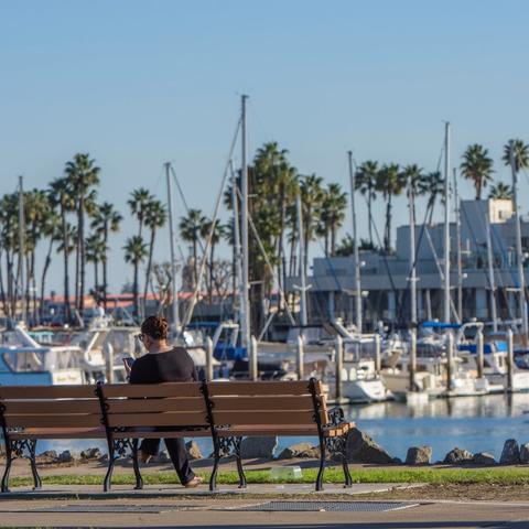 Woman sitting on bench overlooking the marina at Spanish Landing Park at the Port of San Diego