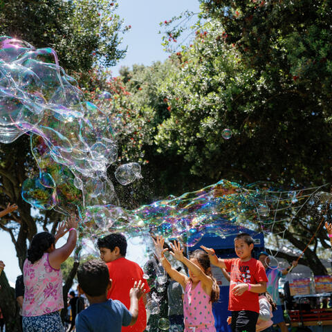 Kids playing with giant bubbles in the park